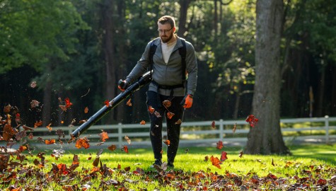 En man som blåser löv med en bensindriven Husqvarna lövblåsare